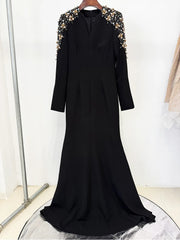 Black dress with gold embellishments on shoulders against a white background