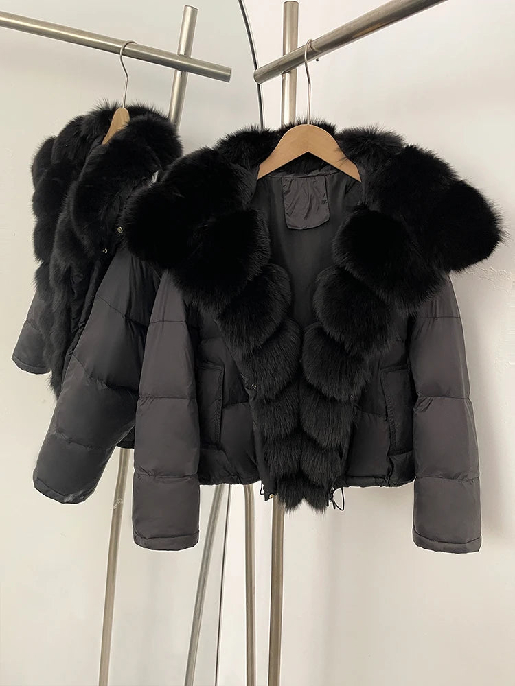 Black puffer jacket with fur trim hanging on a rack against a white background