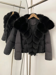 Black puffer jacket with fur trim hanging on a rack against a white background