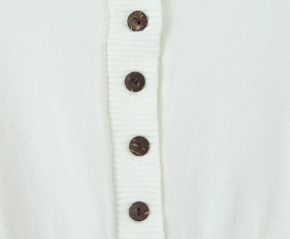 Close-up of a white cardigan with brown buttons on a light gray background