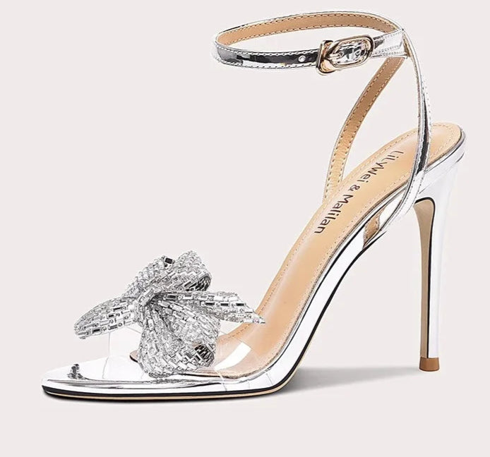 Silver high-heeled sandal with decorative bow on a white background