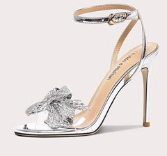 Silver high-heeled sandal with decorative bow on a white background
