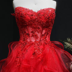 Red evening gown with floral embellishments on a mannequin against a dark background