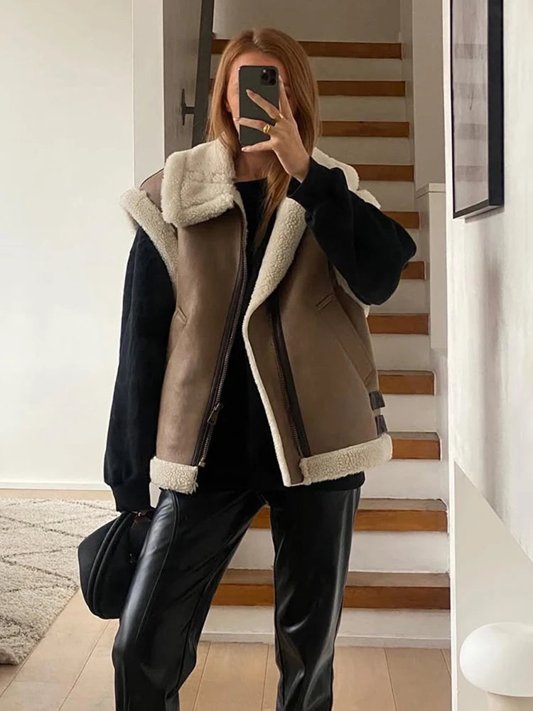 Person wearing a brown shearling jacket with white lining indoors.