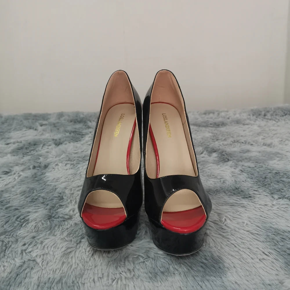 Black high-heeled shoes with red soles on a gray surface