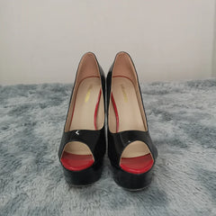 Black high-heeled shoes with red soles on a gray surface