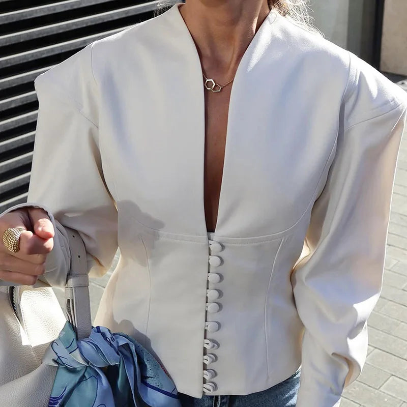 White blouse with a plunging neckline and button details, worn by a person.