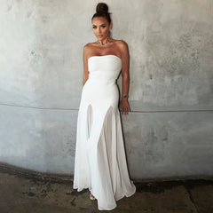 Woman in a strapless white dress standing against a textured wall.
