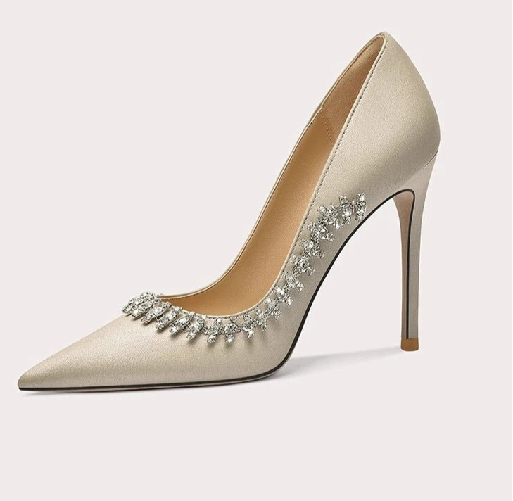 Beige high-heeled shoe with decorative elements on a light gray background