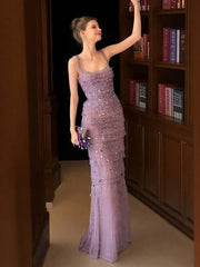 Woman in a purple beaded evening gown standing in front of a bookshelf.
