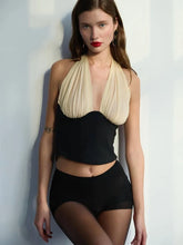 Woman wearing a black and beige two-piece swimsuit against a light background