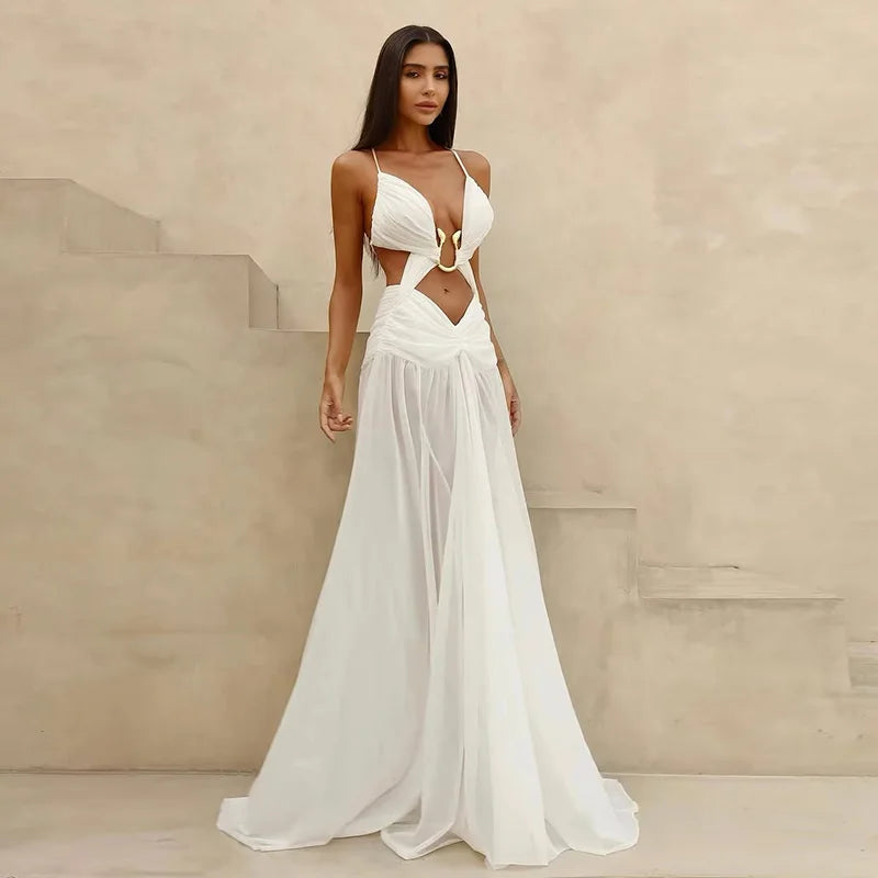 Woman wearing a white dress with cut-out design against a beige wall.