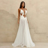 Woman wearing a white dress with cut-out design against a beige wall.