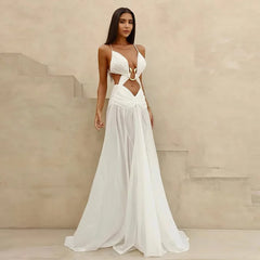 Woman wearing a white dress with cut-out design against a beige wall.