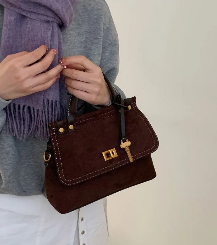 Person holding a brown handbag with a plain background