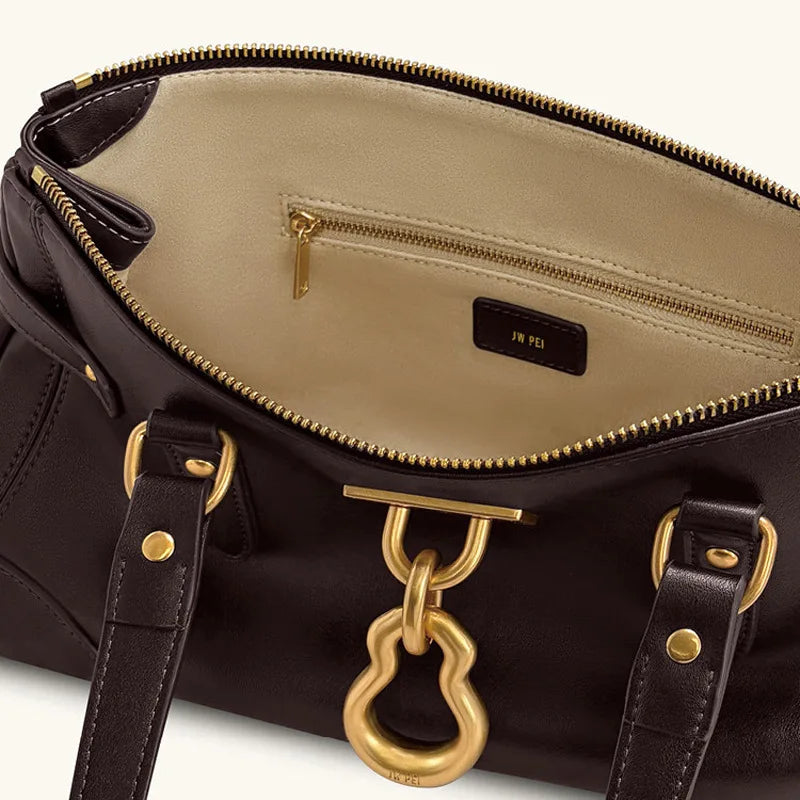 Interior view of a black leather tote bag showing zip pocket and brand tag