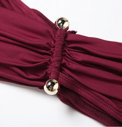 Close-up of a burgundy swimsuit with gold buttons on a white background