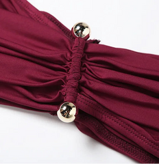 Close-up of a burgundy swimsuit with gold buttons on a white background