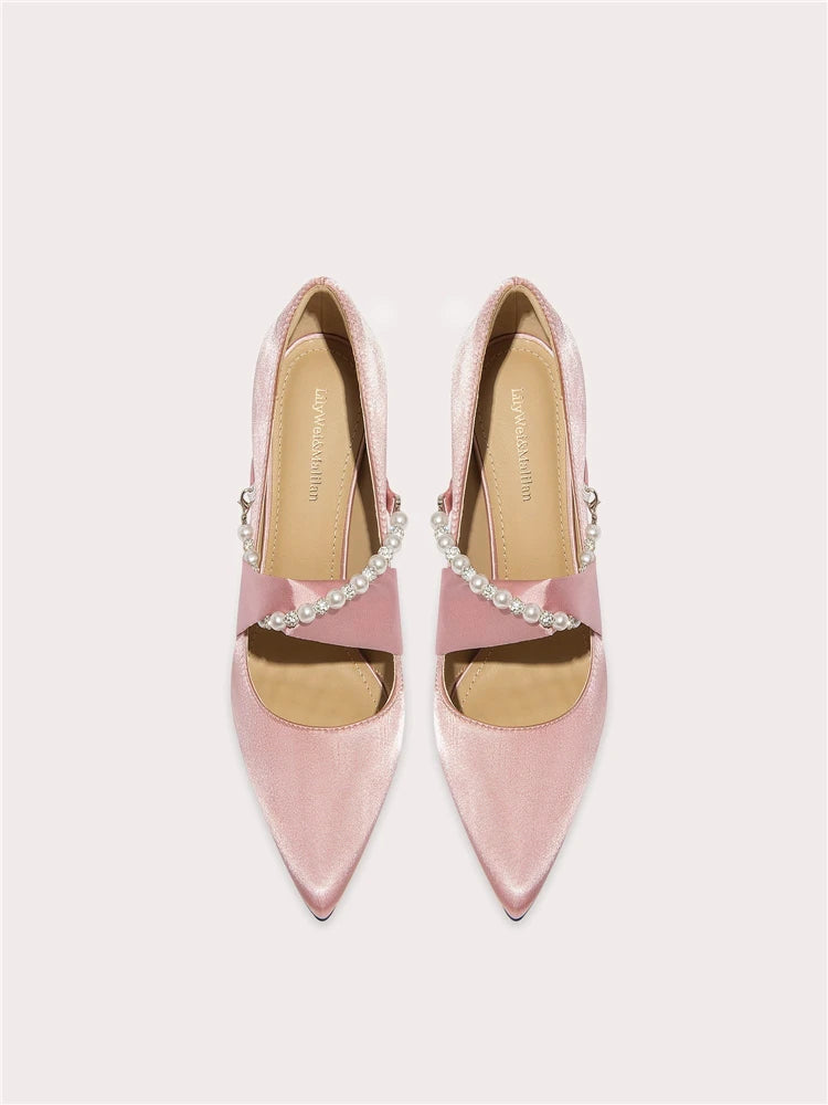 Pair of pink pointed-toe shoes with embellishments on a light gray background
