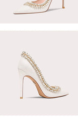 White high-heeled shoes with pearl embellishments on a light gray background