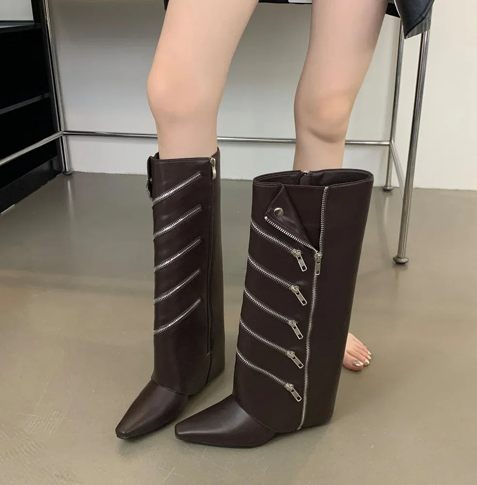 Brown knee-high boots with zippers worn by a person on a neutral background