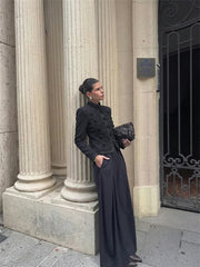 Woman in a black outfit standing against classical columns