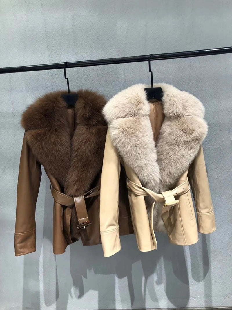 Two leather jackets with fur collars hanging on a rack against a gray background.