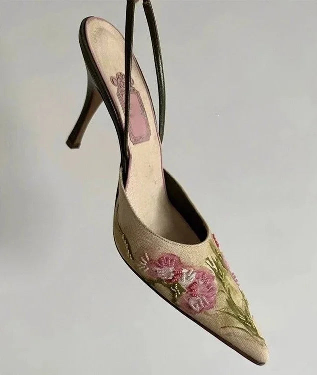 Beige high-heeled shoe with floral embroidery on a light gray background
