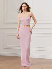 Woman wearing a pink outfit standing against a white wall.