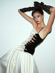 Model wearing a black and white dress with intricate detailing on a plain background