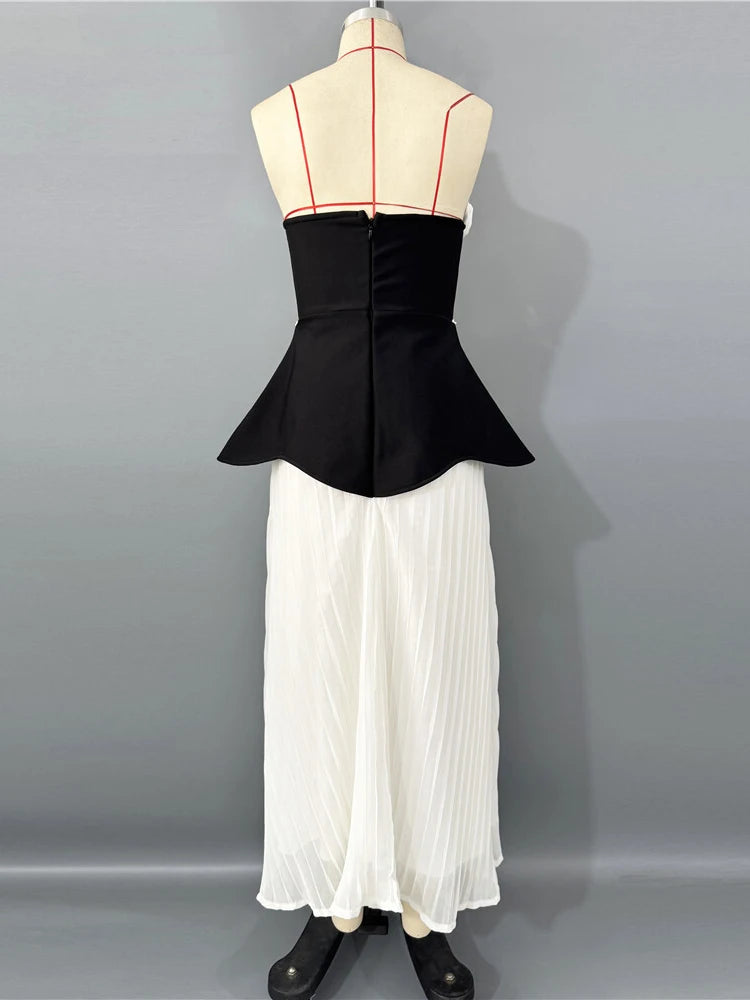 Black peplum top and white pleated skirt on a mannequin against a gray background