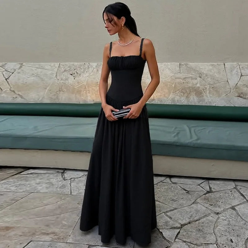 Woman in a black dress standing outdoors on a stone pavement.