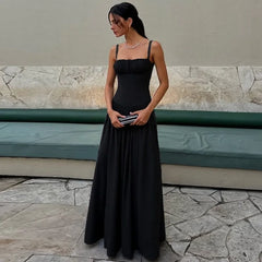 Woman in a black dress standing outdoors on a stone pavement.