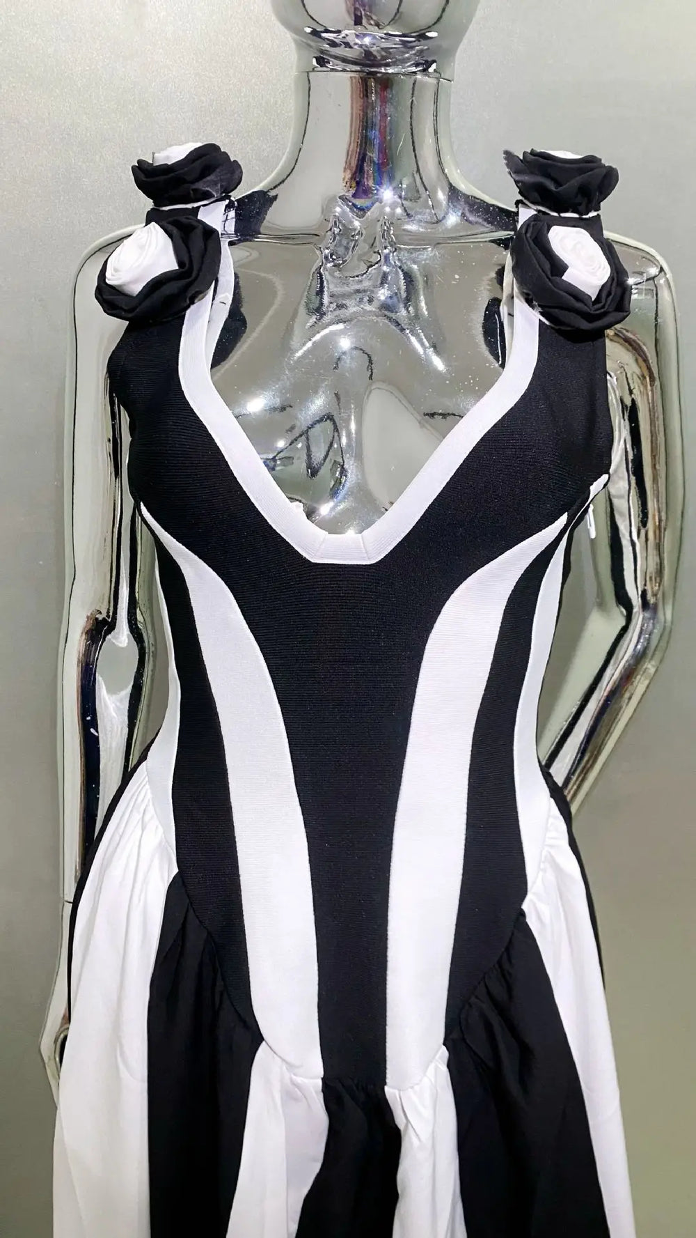 Black and white dress with floral details on a mannequin against a neutral background