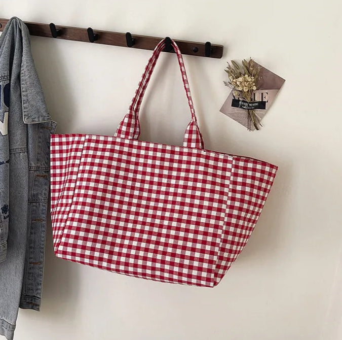 Red and white checkered bag hanging on a wooden rack against a white wall.