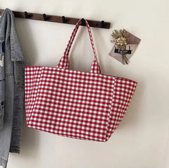 Red and white checkered bag hanging on a wooden rack against a white wall.