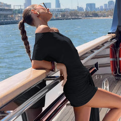 Woman in a black dress on a boat with a city skyline in the background