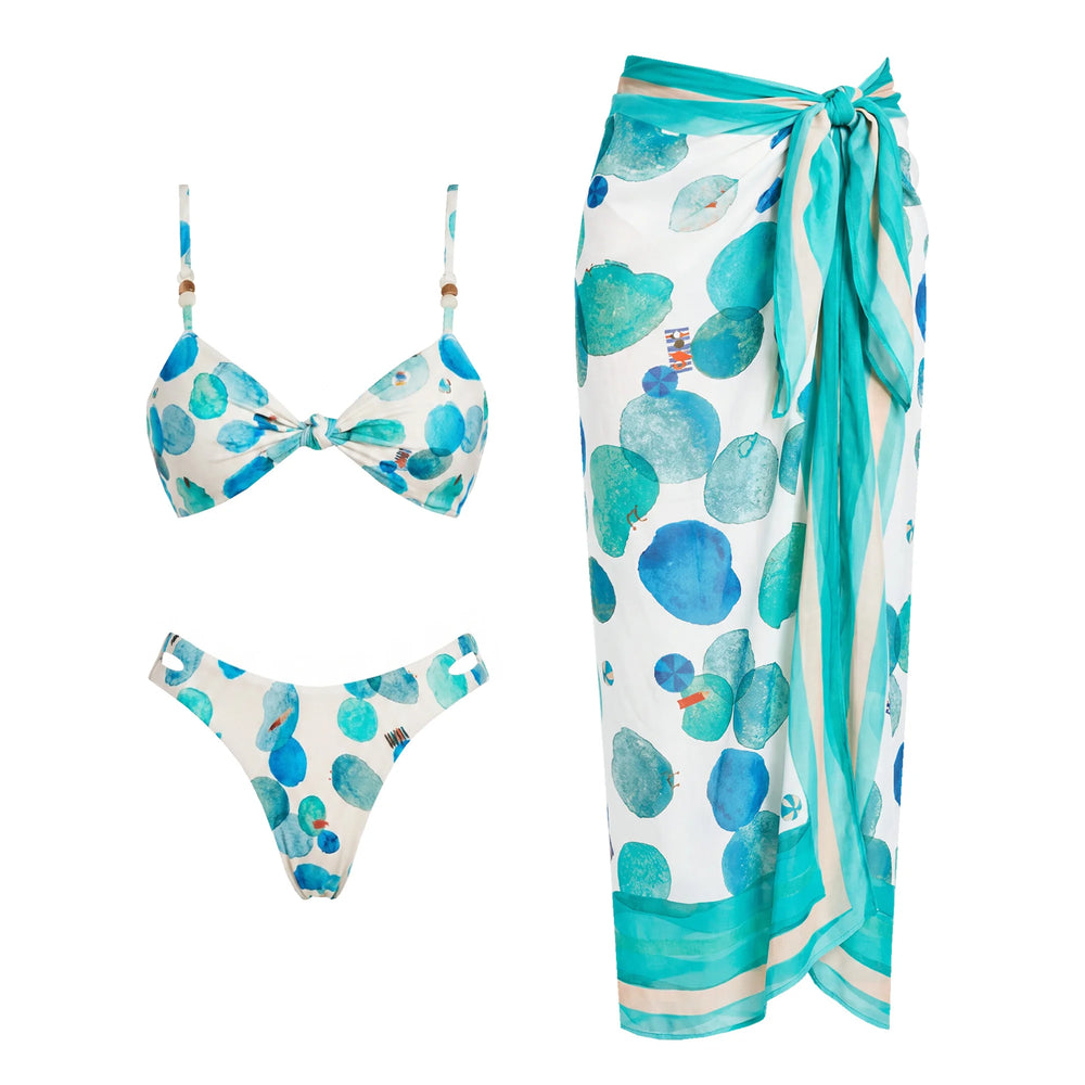 White bikini top and bottom with abstract blue and green dots, and a matching wrap skirt.
