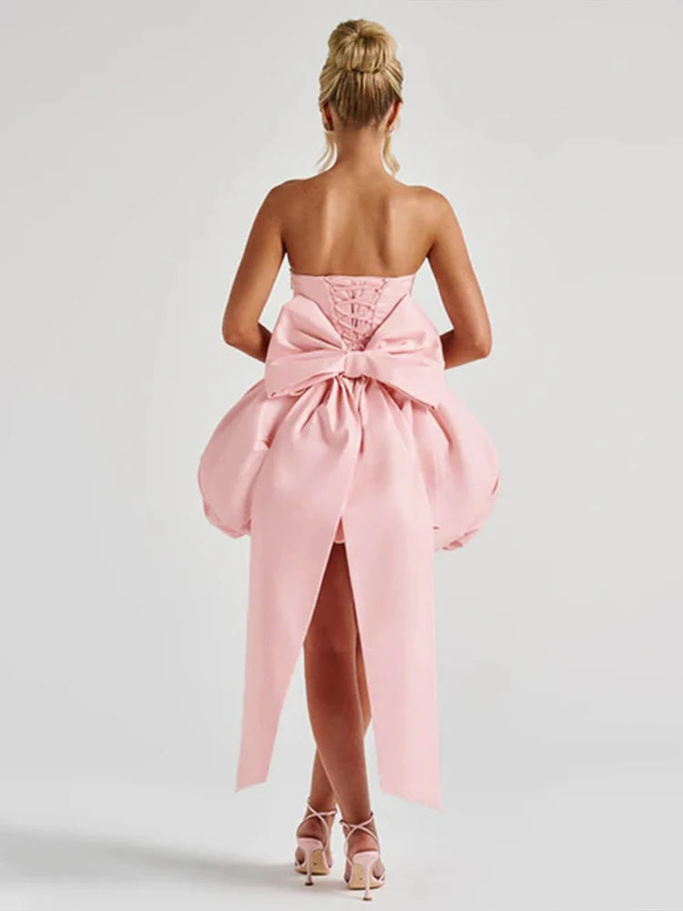 Pink strapless dress with a large bow detail on a white background