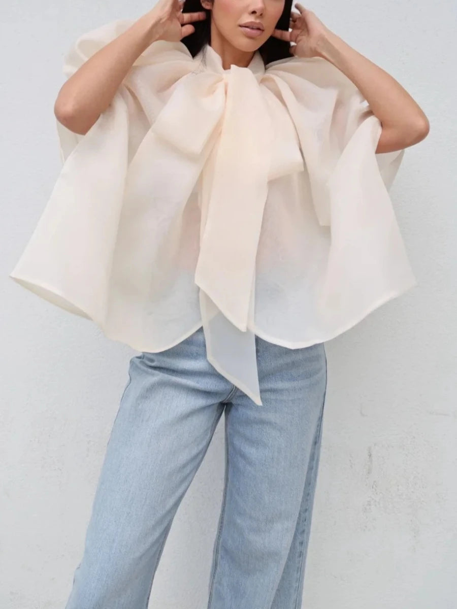 Oversized bow neck cape top in light peach worn with light wash jeans