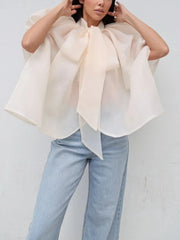 Oversized bow neck cape top in light peach worn with light wash jeans