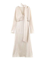 Beige dress with long sleeves and a bow detail on a white background