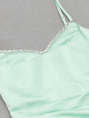 Mint green dress with thin straps and bead detailing on a gray background