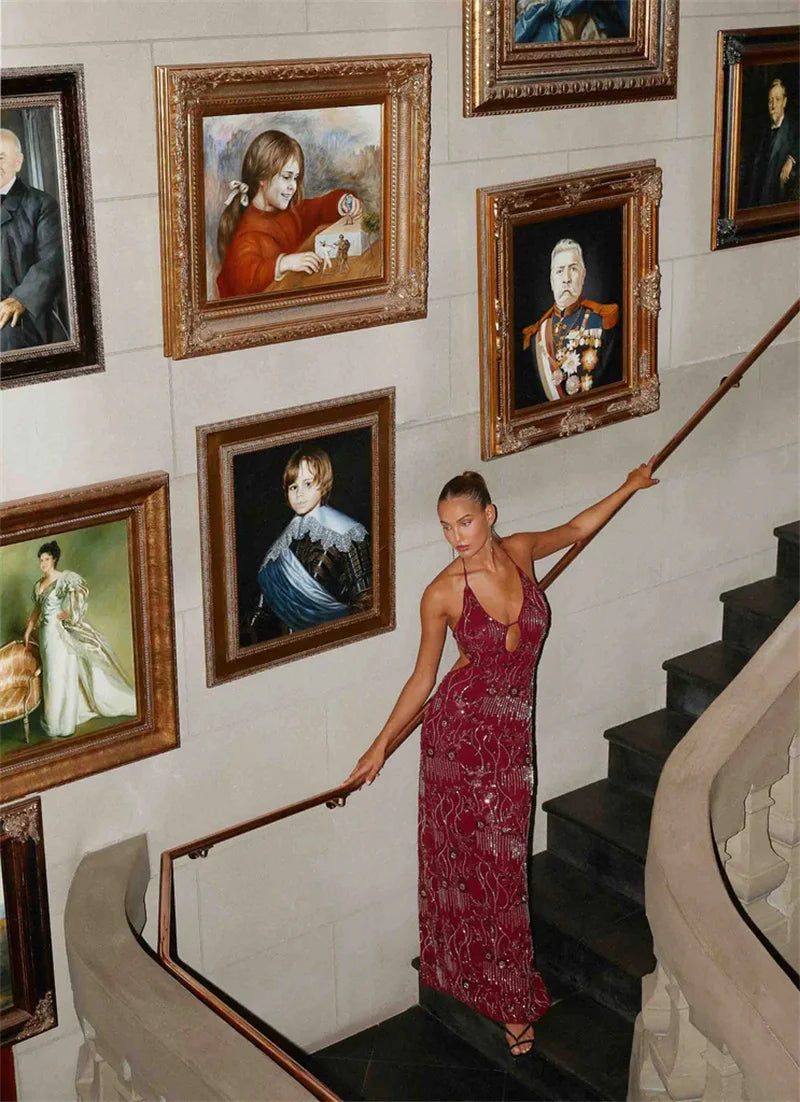 Woman in a red dress standing on a staircase with portraits on the wall