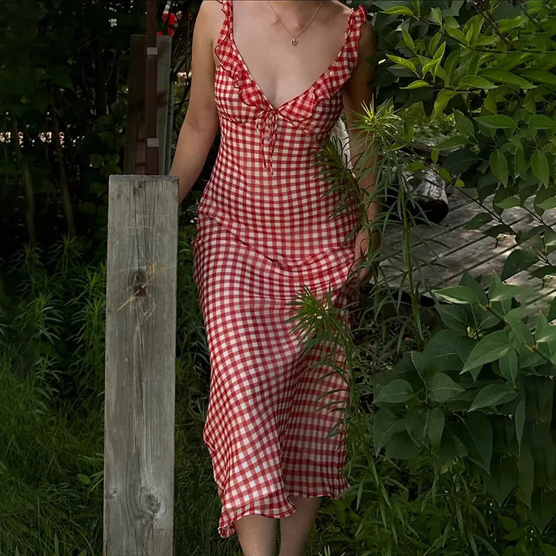 Person wearing a red and white checkered dress standing in a garden.