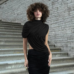 Woman in a black dress standing on stone steps with a stone wall background