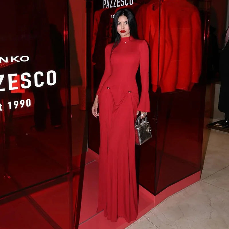 Woman in a red dress standing in front of a store entrance with 'Pazsco' branding.