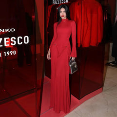 Woman in a red dress standing in front of a store entrance with 'Pazsco' branding.