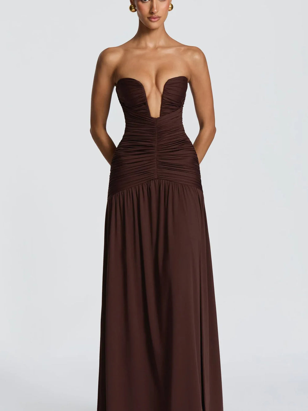 Brown strapless evening gown on a model against a light gray background