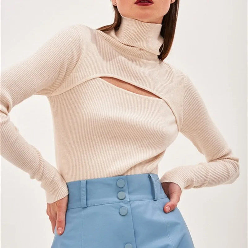 Woman wearing a beige ribbed sweater and light blue pants on a white background